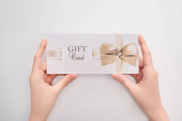 Top view of woman holding gift card in hands on white background — Stock Photo