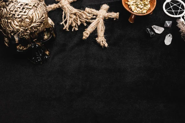 Top view of voodoo dolls, skull and sagebrush in bowl near pentagram and crystals on black — Stock Photo
