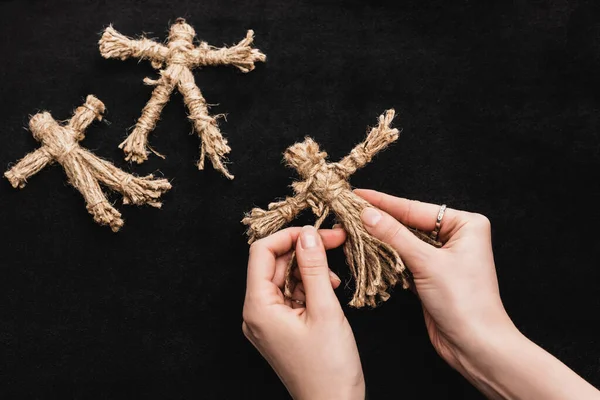 Top view of witch holding voodoo doll on black — Stock Photo