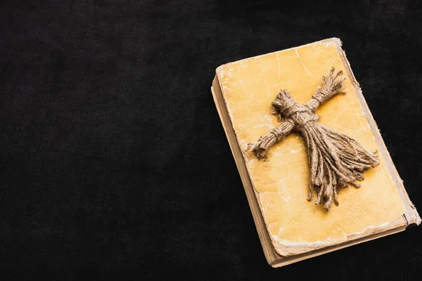 Top view of voodoo doll on aged book on black — Stock Photo