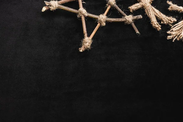 Top view of voodoo doll near pentagram with wooden sticks on black — Stock Photo