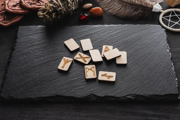 Top view of scandinavian runes near stones and dried herb on black surface — Stock Photo