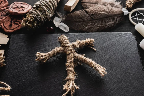 Voodoo doll near feathers and crystals on black surface — Stock Photo