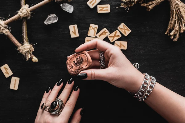 Top view of witch near runes and crystals on black — Stock Photo