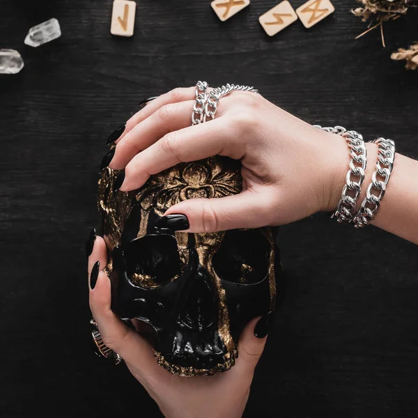 Primo piano della donna che tiene il cranio vicino a rune e cristalli sul nero — Foto stock