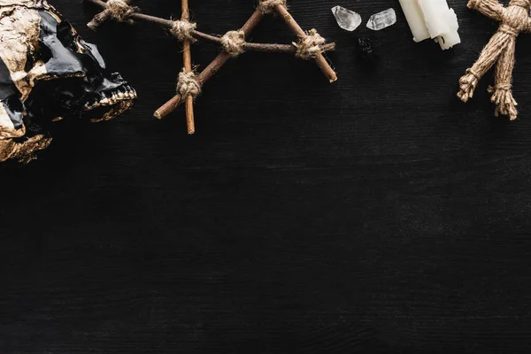 Top view of skull, pentagram, candles, crystals and voodoo doll on black — Stock Photo