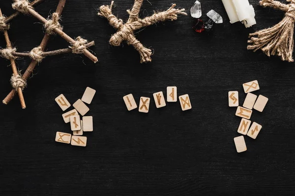 Top view of scandinavian runes, pentagram, candles, crystals and voodoo dolls on black — Stock Photo