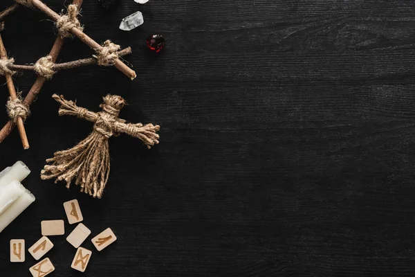 Vista dall'alto di bambole voodoo, rune antiche, pentagramma, candele e cristalli su nero — Stock Photo