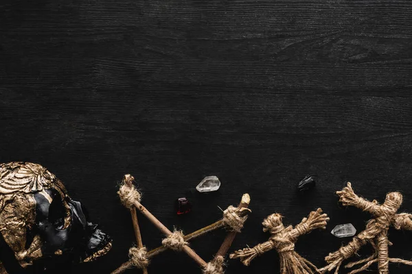 Top view of voodoo dolls, ancient crystals, pentagram and skull on black — Stock Photo