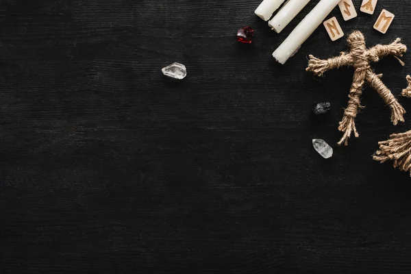 Top view of candles near crystals, voodoo doll and runes on black — Stock Photo