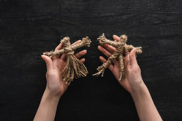 Cropped view of witch holding voodoo dolls in hands on black — Stock Photo