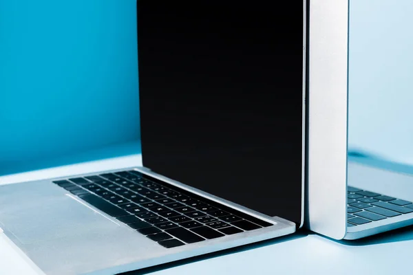 Modern open laptops with blank screen on blue workplace — Stock Photo