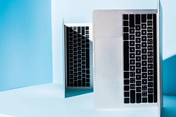 Portátiles modernos en el lugar de trabajo azul con luz solar - foto de stock