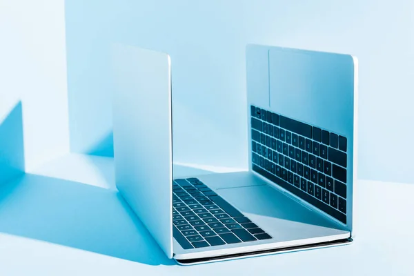 Сучасні ноутбуки на синьому робочому місці в сонячному світлі — стокове фото