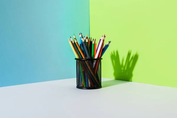 Тримач для олівців з кольоровими олівцями на синьому, зеленому та білому тлі — стокове фото