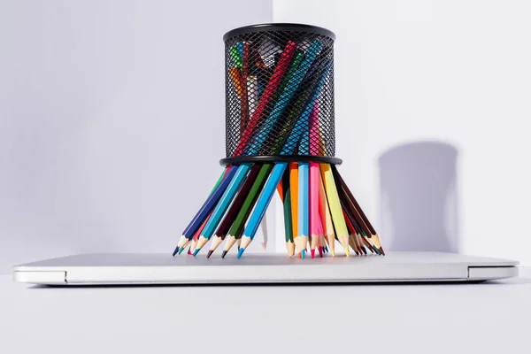 Colored pencils in pencil holder on modern laptop on white background — Stock Photo