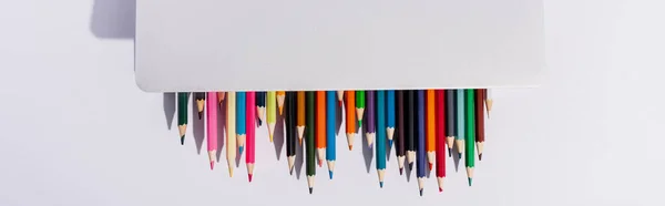 Top view of colored pencils in modern laptop on white background, panoramic shot — Stock Photo