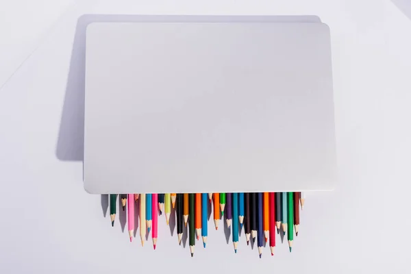 Top view of colored pencils in modern laptop on white background — Stock Photo