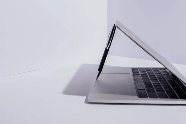 Pluma en el ordenador portátil moderno sobre fondo blanco - foto de stock