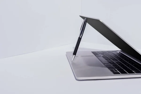 Pluma en el ordenador portátil moderno sobre fondo blanco - foto de stock