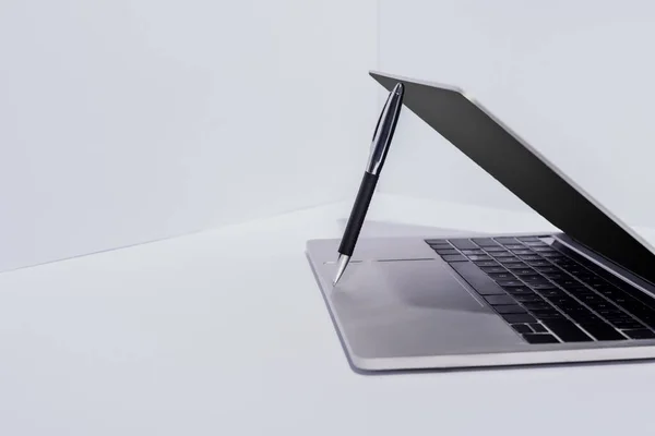 Pen in modern laptop on white background — Stock Photo