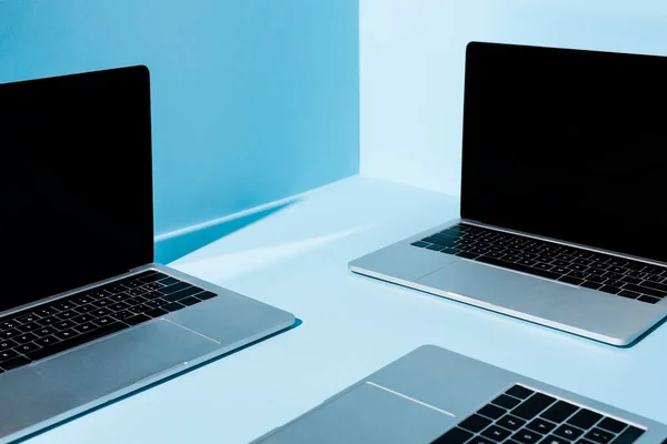 Modern laptops with blank screens on blue background — Stock Photo