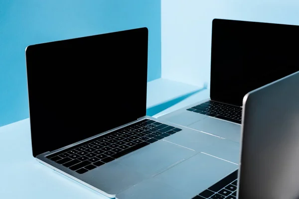 Modern laptops with blank screens on blue background — Stock Photo