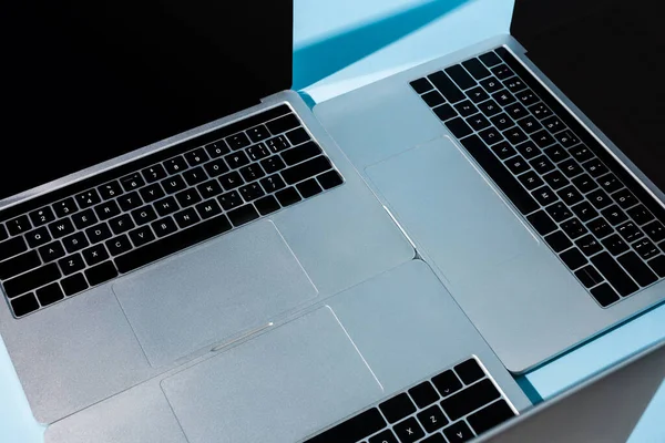 Modern laptops with keyboards on blue background — Stock Photo