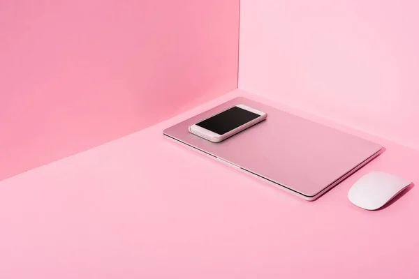 Portátil, smartphone y ratón de ordenador sobre fondo rosa - foto de stock