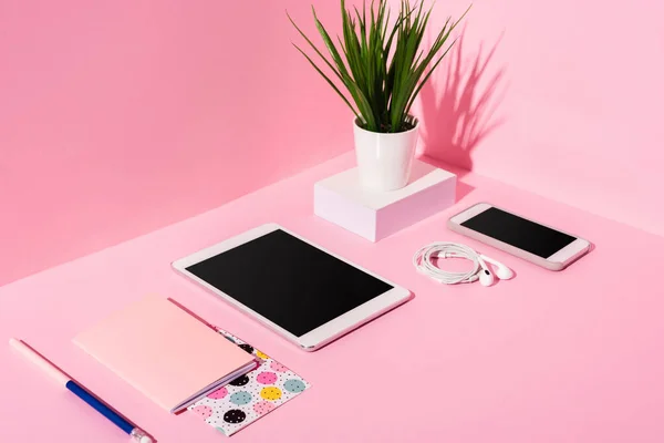 Gadgets modernes avec écrans vierges, papeterie, écouteurs et plante sur fond rose — Photo de stock