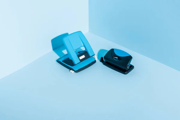 Blue plastic hole puncher on blue background — Stock Photo