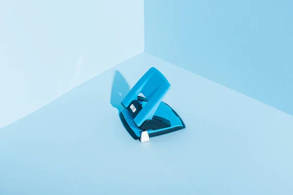 Blue plastic hole puncher on blue background — Stock Photo