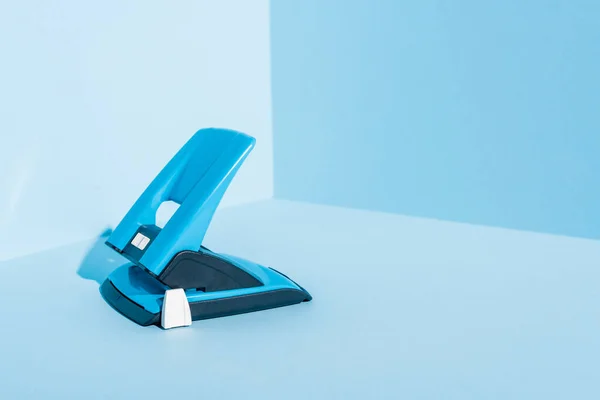 Blue plastic hole puncher on blue background — Stock Photo