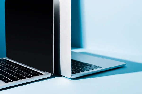 Сучасні ноутбуки на синьому робочому місці у світлі — стокове фото