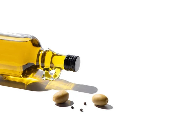 Olive oil in bottle near green olives and black pepper on white background — Stock Photo
