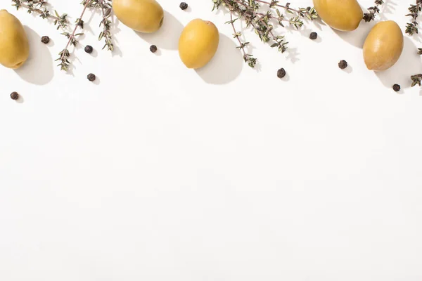 Vista dall'alto di olive verdi, erbe aromatiche e pepe nero su sfondo bianco — Foto stock