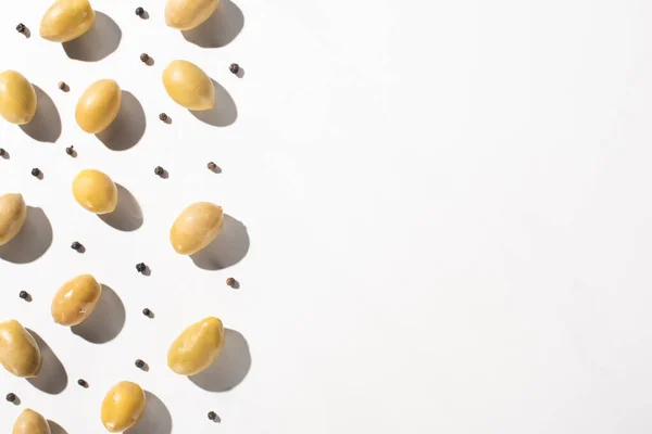 Top view of green olives and black pepper on white background — Stock Photo