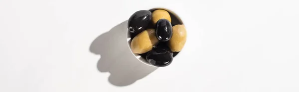 Vue de dessus des olives noires et vertes dans un bol sur fond blanc, orientation panoramique — Photo de stock