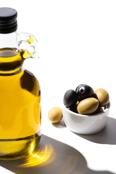 Azeite em garrafa perto de azeitonas verdes e pretas em tigela sobre fundo branco — Fotografia de Stock
