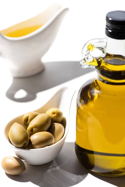 Selektiver Fokus von Olivenöl in Flasche und Soße Boot in der Nähe von grünen Oliven in Schüssel auf weißem Hintergrund — Stockfoto