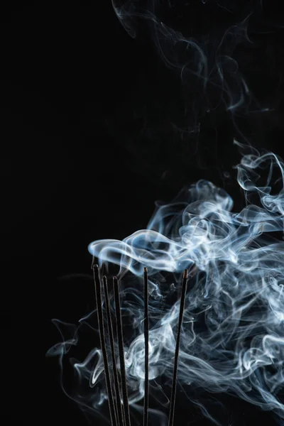 Палаючі палички аромату з димом на чорному фоні — стокове фото