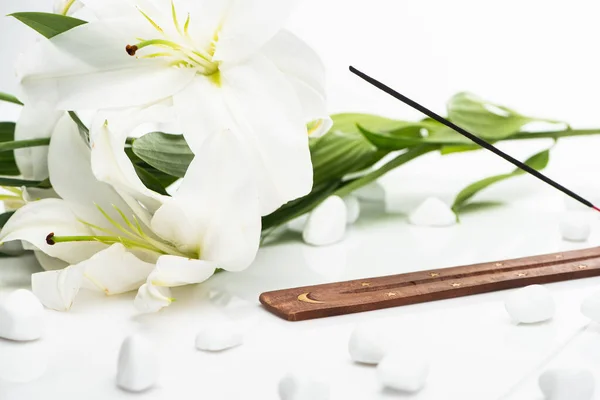 Aroma stick on wooden stand near lilies on white background — Stock Photo