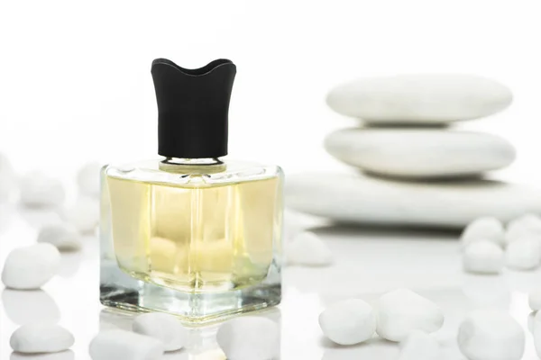 Selektiver Fokus von Parfüm in der Flasche in der Nähe von Wellness-Steinen auf weißem Hintergrund — Stockfoto