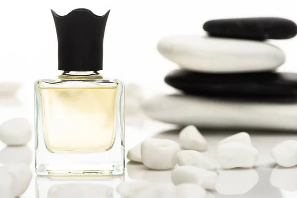 Selective focus of home perfume in bottle near spa stones on white background — Stock Photo