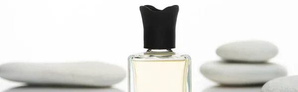 Selective focus of home perfume in bottle near spa stones isolated on white background, panoramic shot — Stock Photo