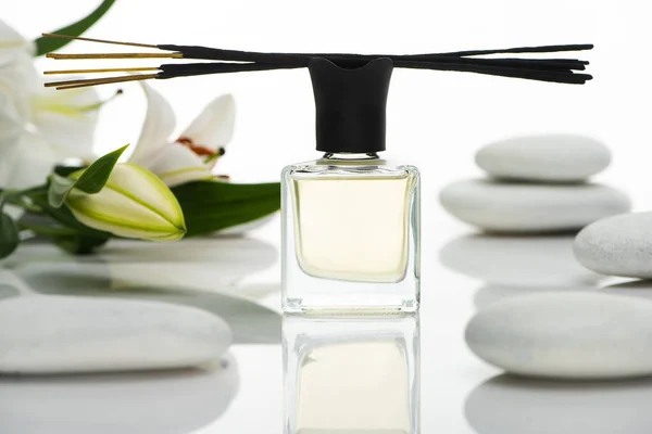 Selective focus of aroma sticks and perfume near spa stones and lilies isolated on white — Stock Photo