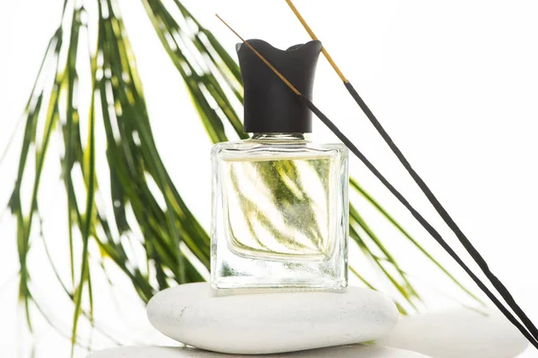 Selective focus of aroma sticks near perfume in bottle on spa stone on white background — Stock Photo