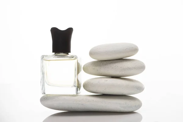 Casa perfume em garrafa perto de pedras de spa no fundo branco — Fotografia de Stock