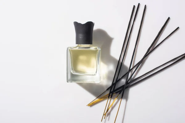 Vista superior de varas de aroma perto de perfume em garrafa no fundo branco — Fotografia de Stock