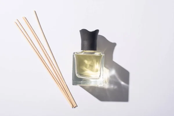 Vista superior de varas de aroma perto de perfume em garrafa no fundo branco — Fotografia de Stock